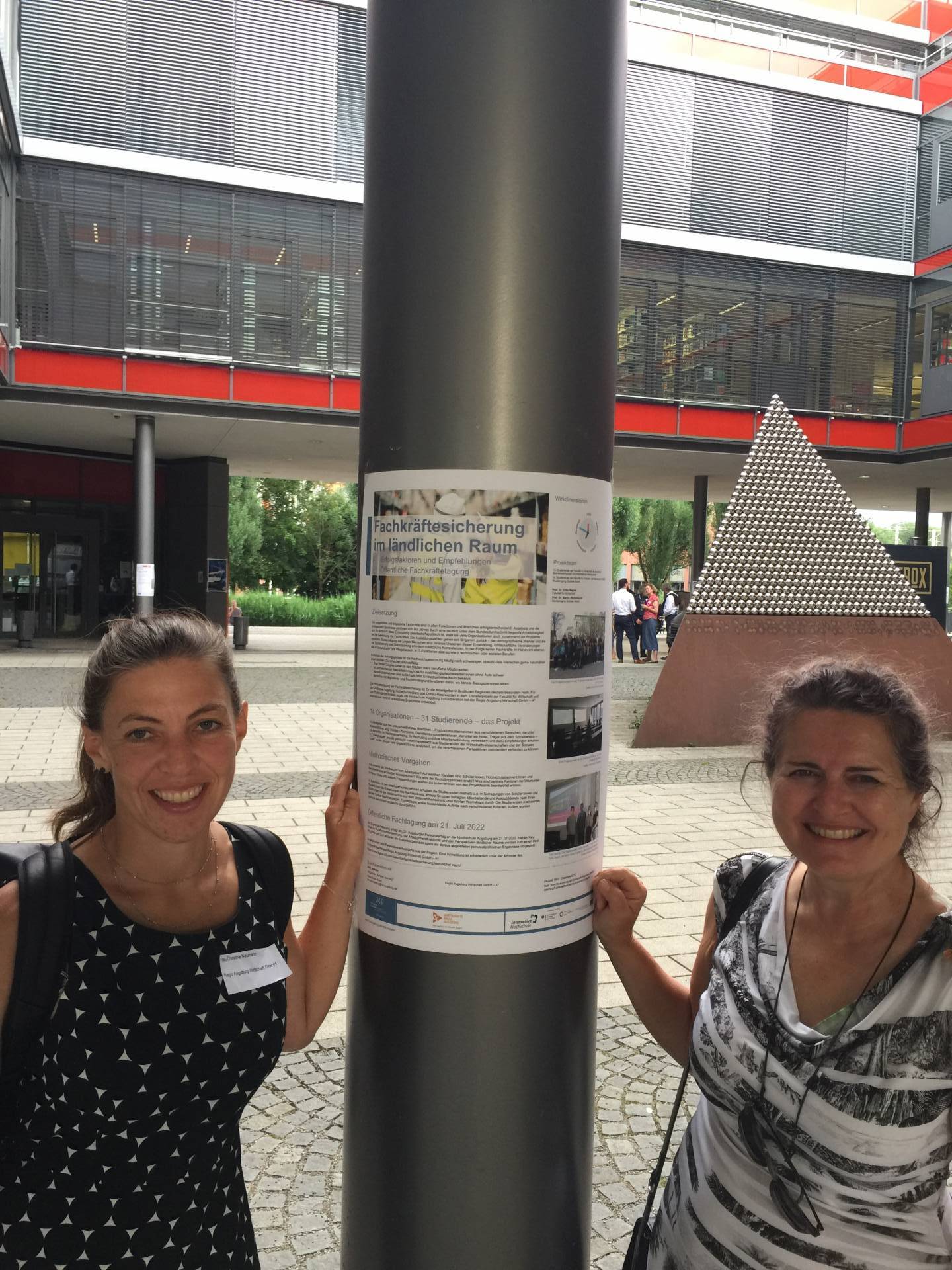 Am Projektposter Fachkräftesicherung im ländlichen Raum: Die Transferpartnerinnen (von links) Christine Neumann, Regio Augsburg Wirtschaft GmbH, und Prof. Dr. Erika Regnet, Fakultät für Wirtschaft © A3 Regio