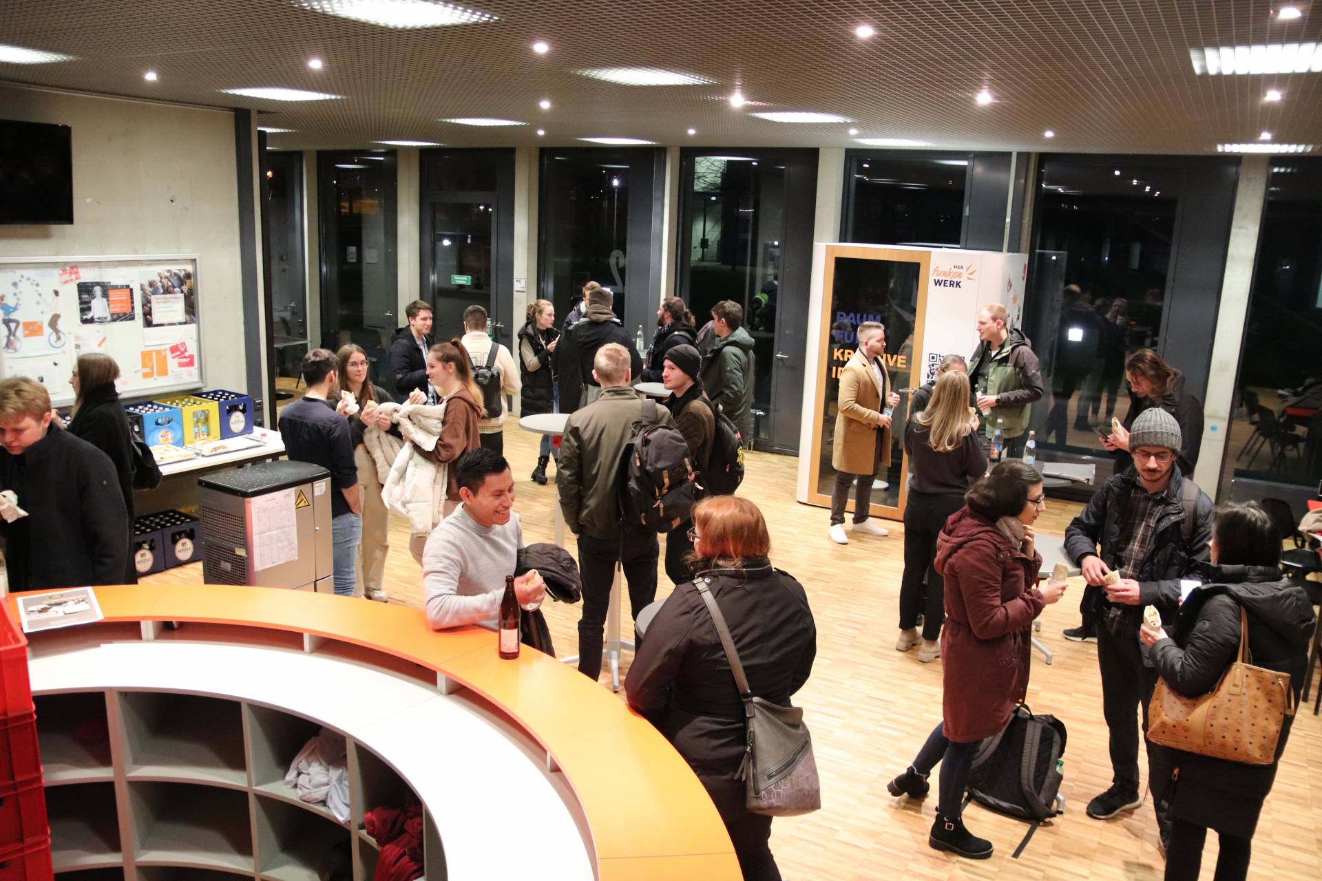 Studierende, Mitarbeitende und Redner beim gemeinsamen Get-Together im Foyer der Hochschule Augsburg.