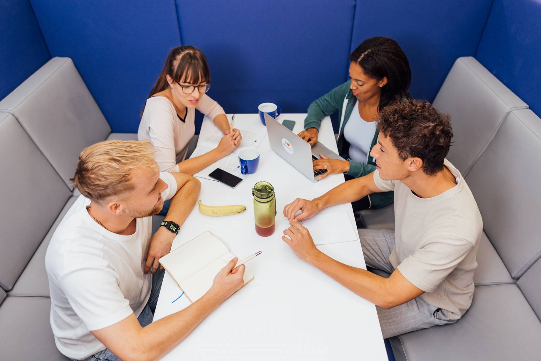 Studierende sitzen an einem Tisch und arbeiten in der Gruppe