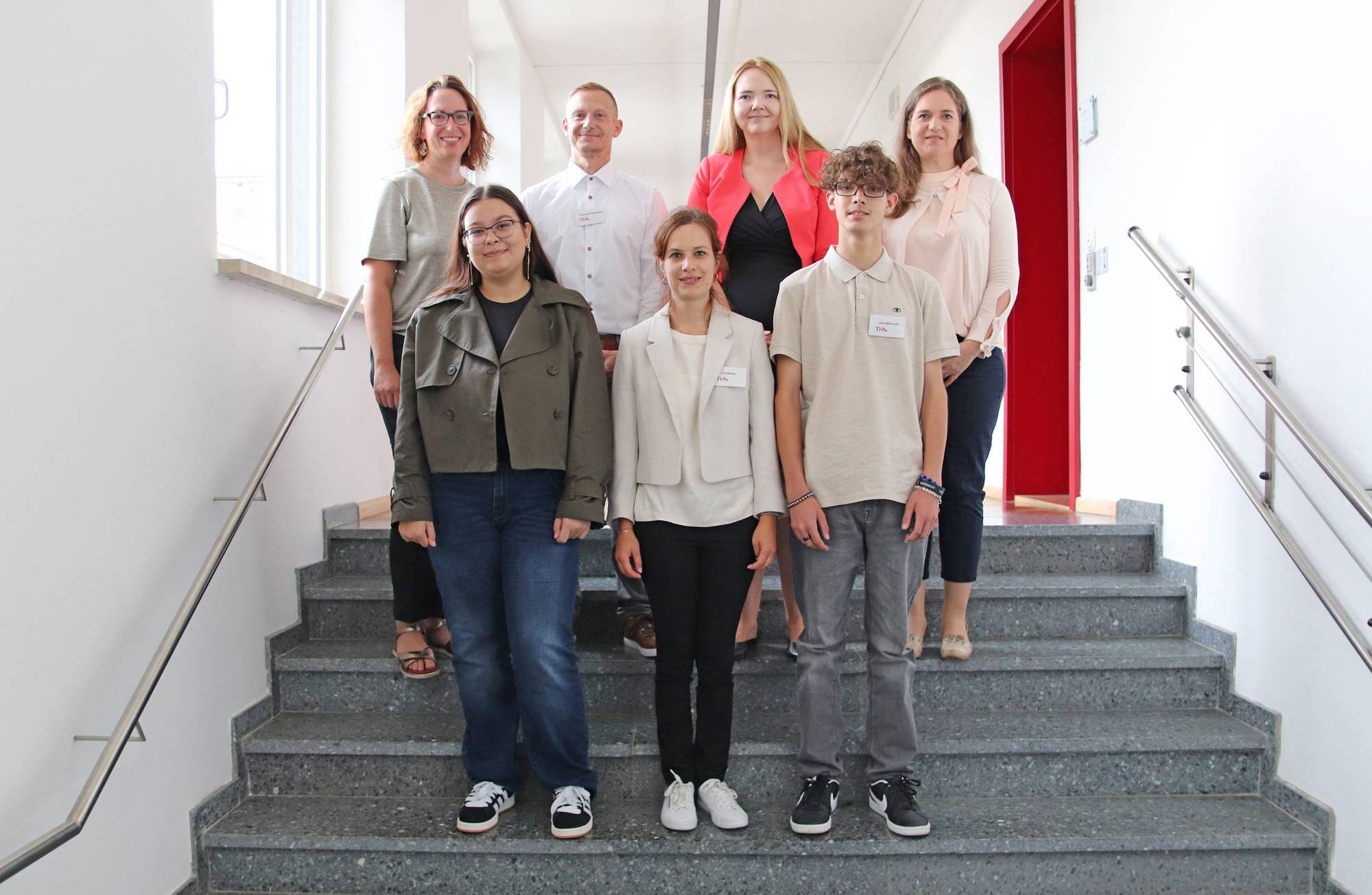 Sila Göcmen (2. v. l), Iris Müller (Mitte) und Leon Marcroft (2. v. r.), mit Kanzlerin Sandra Scholl und den Abteilungsleitungen.