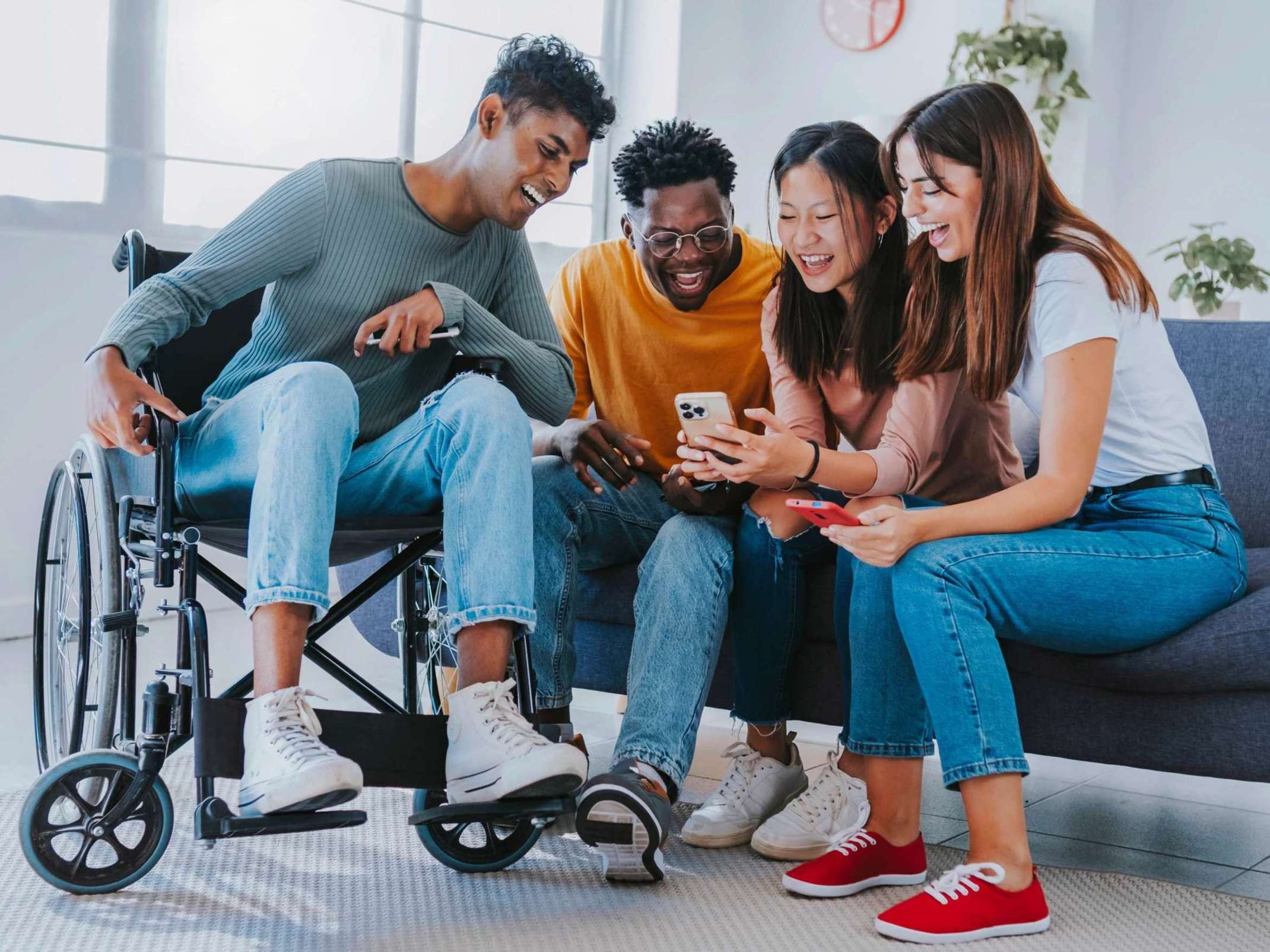 Studenten auf Couch und in Rollstuhl mit Handy Studenten auf Couch und in Rollstuhl mit Handy