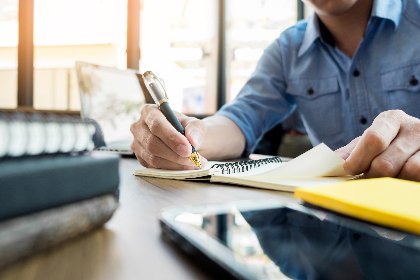 Person sitzt am vollen Arbeitstisch