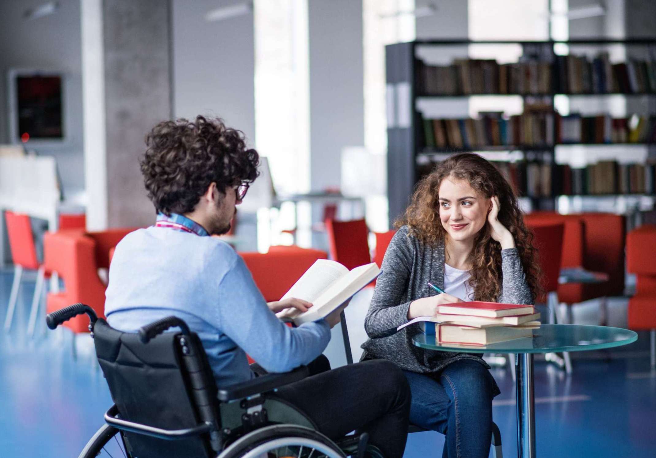 Studierende mit sichtbarer und unsichtbarer Behinderung am Campus mit Büchern auf dem Tisch Studierende mit sichtbarer und unsichtbarer Behinderung am Campus mit Büchern auf dem Tisch